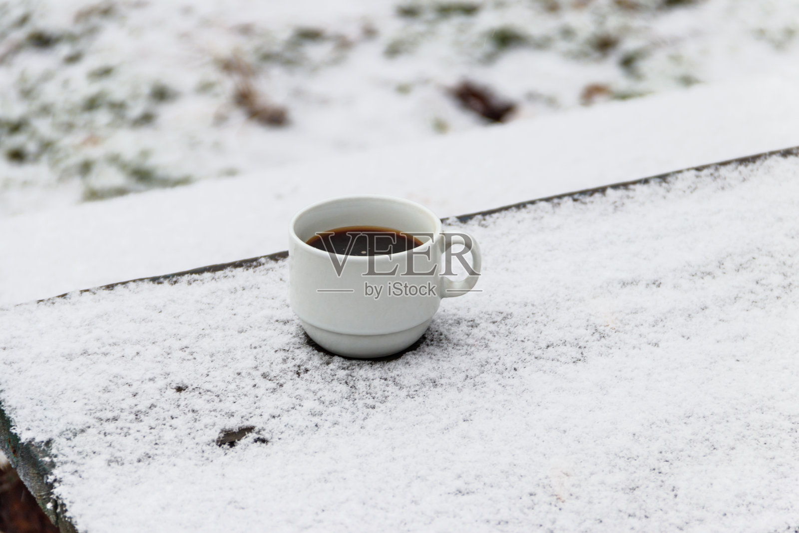 在冬天,在被雪覆盖的桌子上喝一杯咖啡照片摄影图片