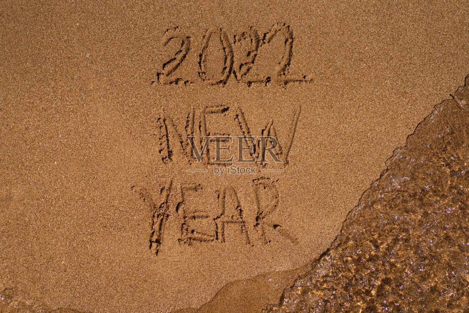 在沙滩上祝2022年新年快乐。沙滩上的沙子和海边的波浪。照片摄影图片