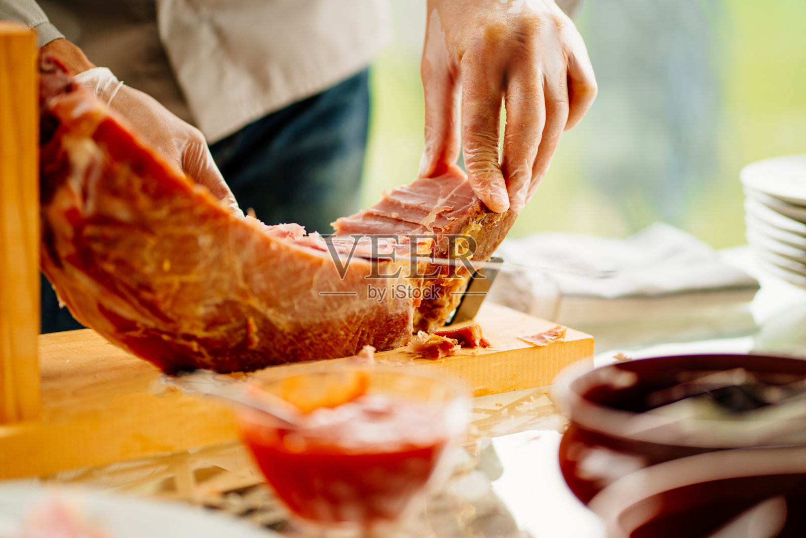 一个戴着手套的男人正在为宴会切肉干。照片摄影图片