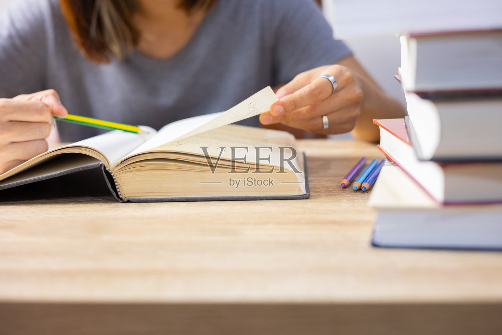 图为一名妇女在桌上阅读课本的特写镜头和选择性聚焦镜头,展现了在大学里努力学习、学习考知识、成功人生的教育理念。照片摄影图片