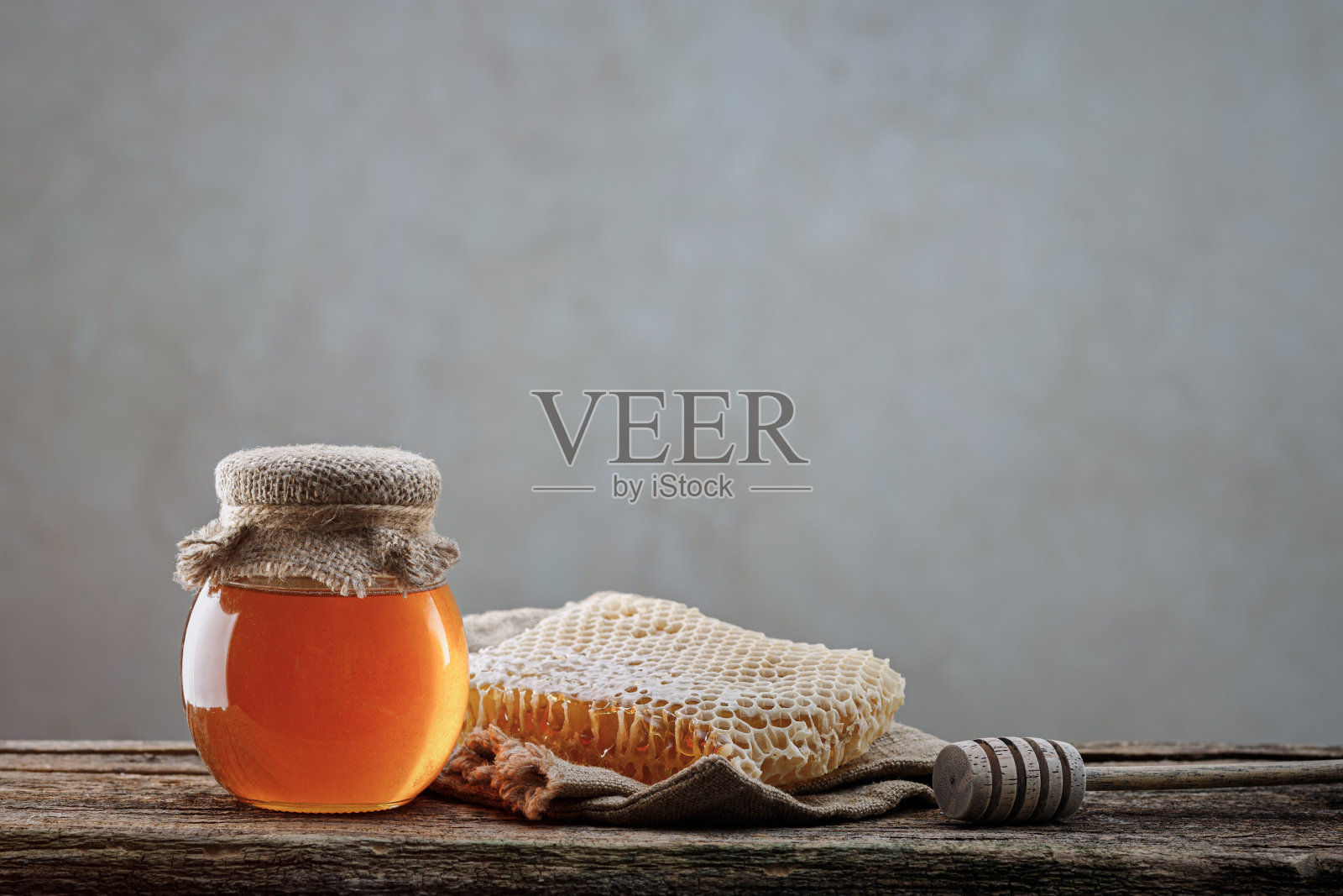 蜂蜜的背景。蜜糖在蜂巢里,玻璃瓶里。木制背景照片摄影图片