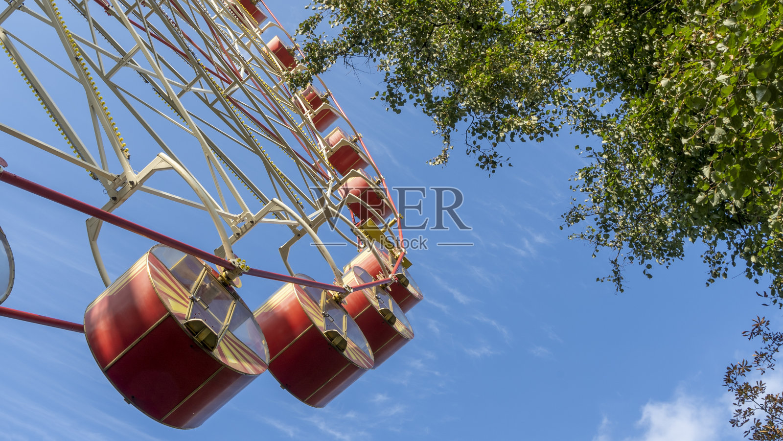 带客舱的摩天轮。游乐园里蓝天下的旋转木马。照片摄影图片