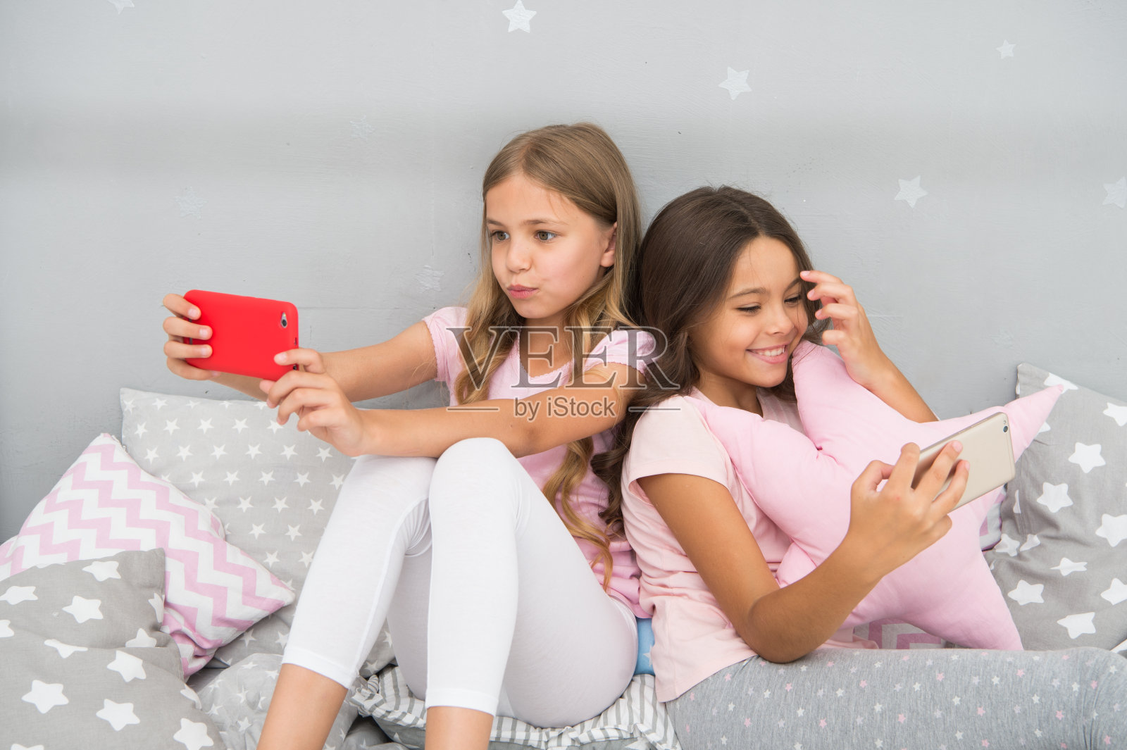 少女休闲睡衣派对。女孩们用智能手机写小博客。在线娱乐。探索社交网络。智能手机的娱乐。孩子有问题。智能手机应用程序的概念照片摄影图片