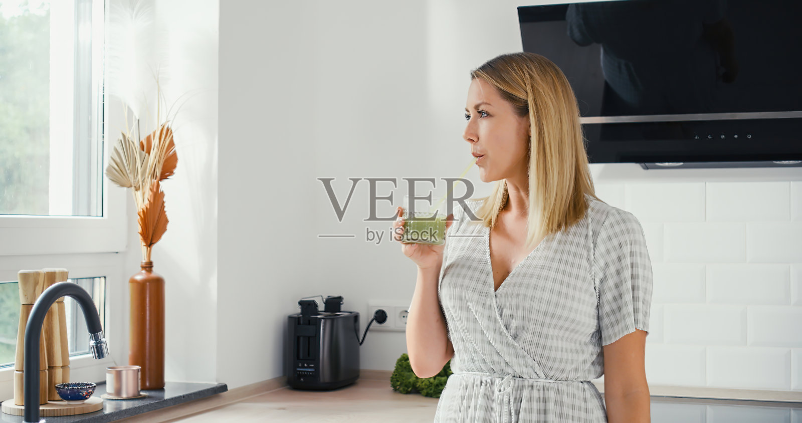 年轻女子在漂亮的厨房里喝绿冰沙照片摄影图片