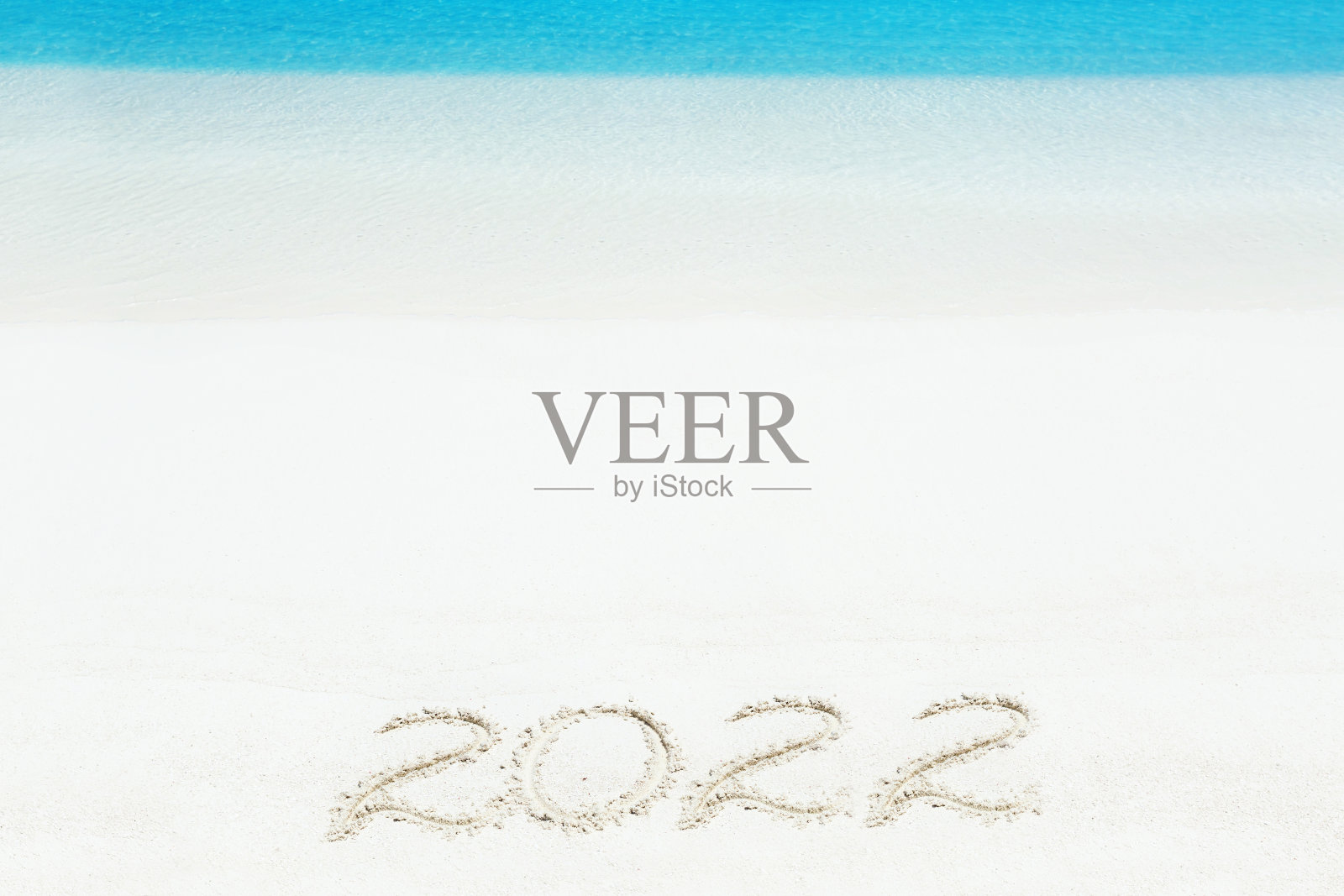 在海滩上庆祝2022年新年。写在沙滩上的碑文照片摄影图片