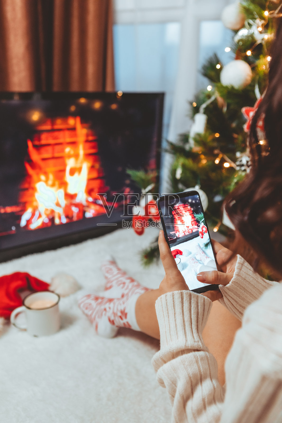 一个女人在圣诞树和壁炉旁用手机拍照照片摄影图片