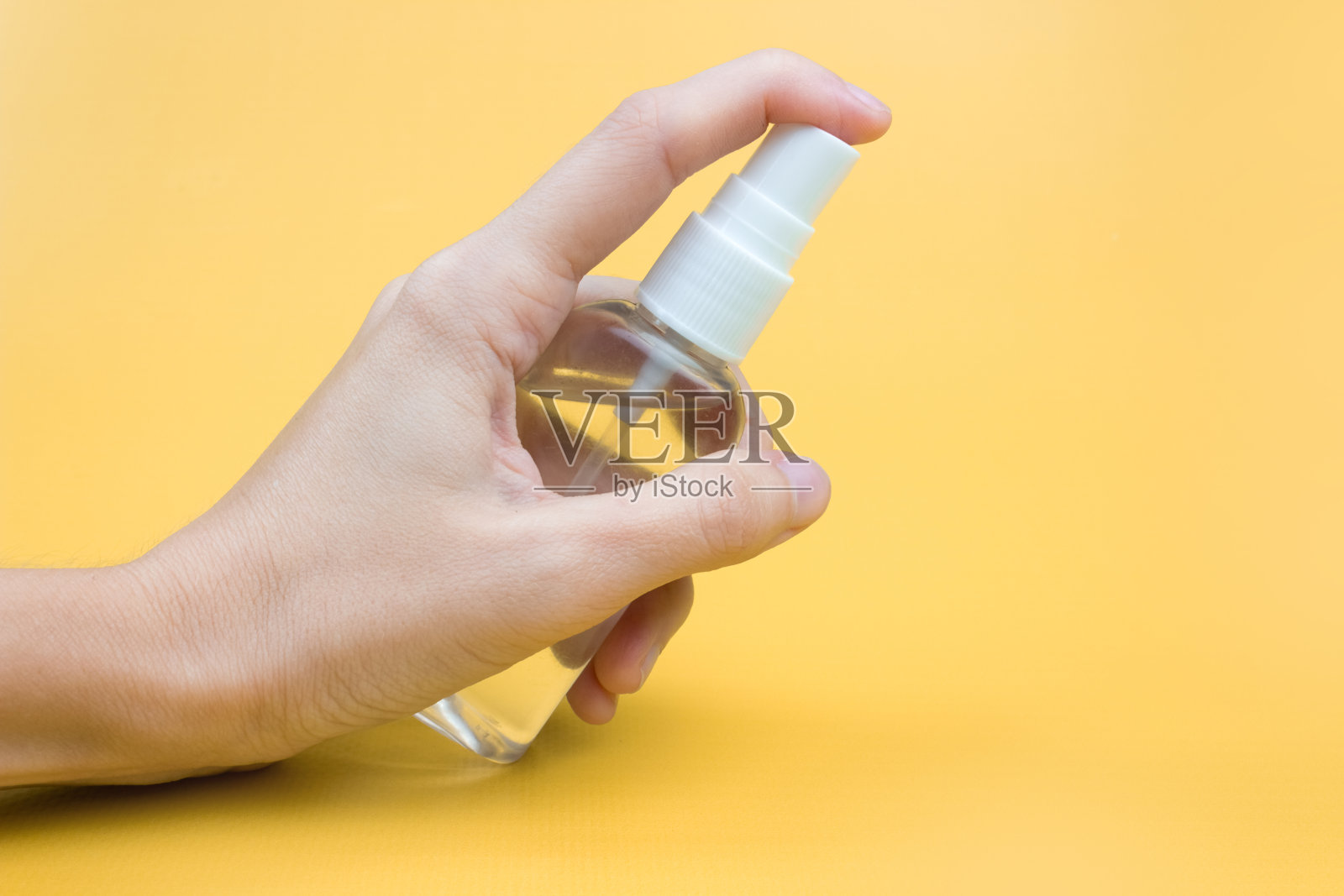 一个女人的手在一个黄色的背景上用防腐剂。卫生和清洁的概念。消毒液照片摄影图片