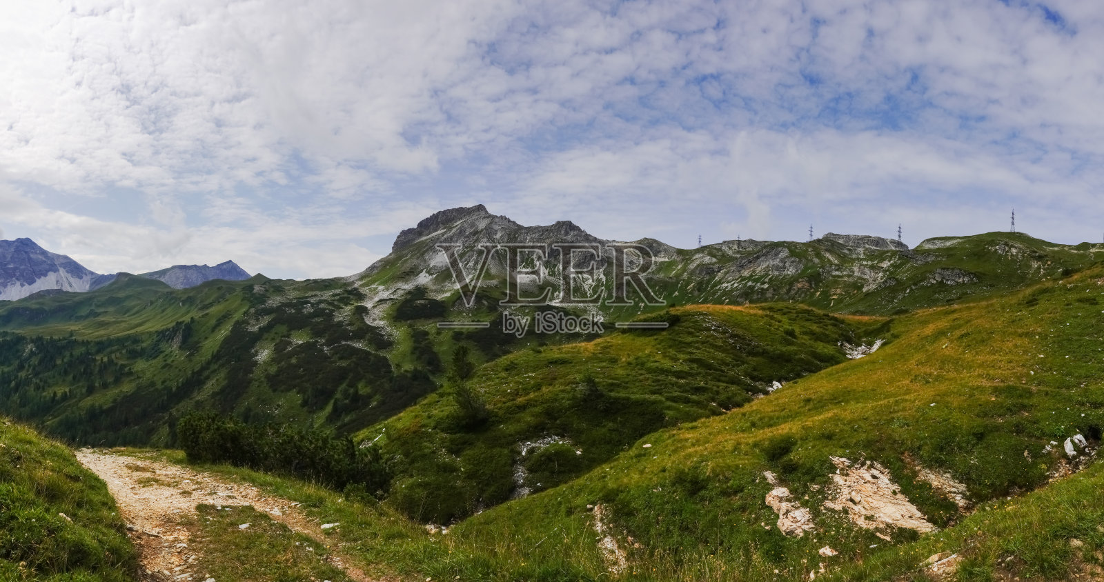 在一条土路上徒步旅行时,可以看到带有电塔的落基山脉照片摄影图片