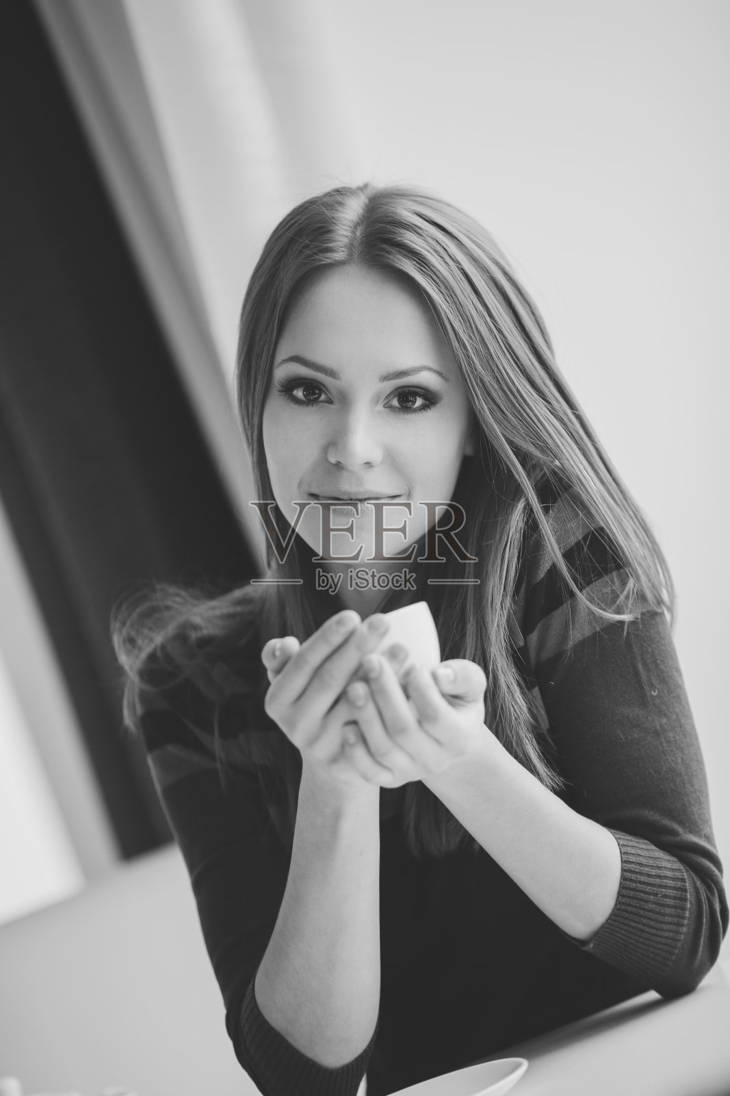 一个可爱微笑的年轻女子的肖像在咖啡馆的桌子上喝着一杯茶。照片摄影图片