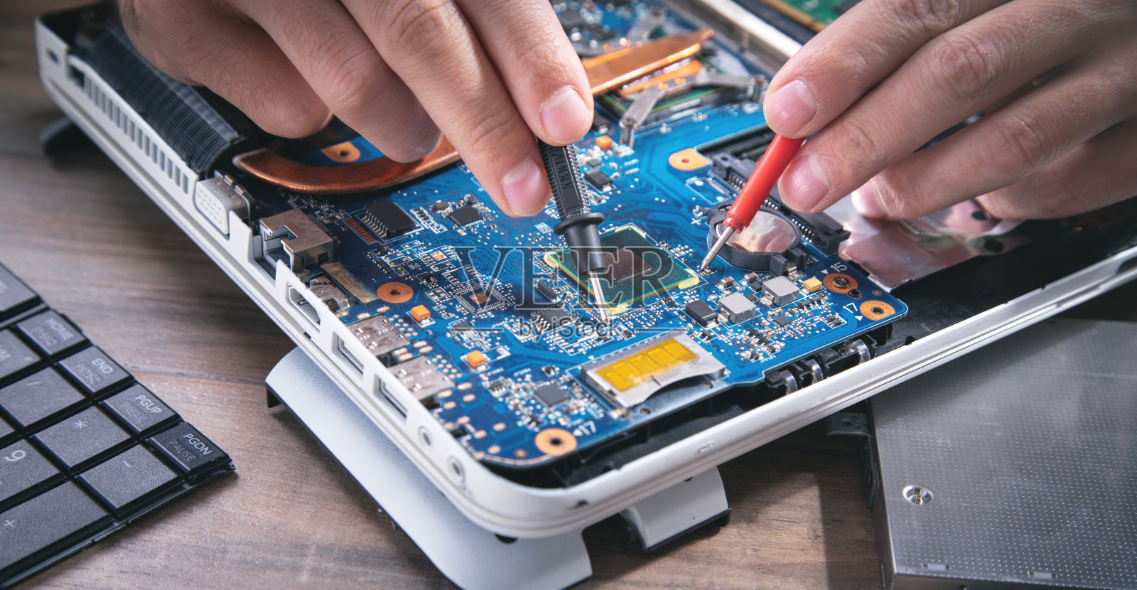 技术人员用万用表手动检查主板。照片摄影图片