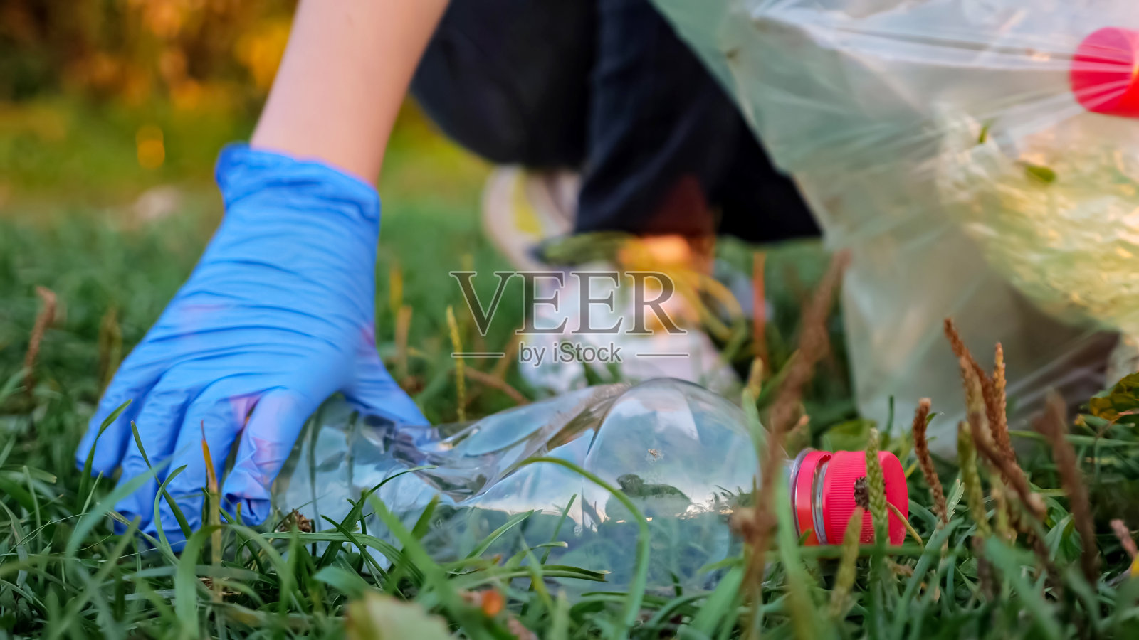 不认识的人用手套收集垃圾,模糊的背景,塑料瓶的特写照片摄影图片