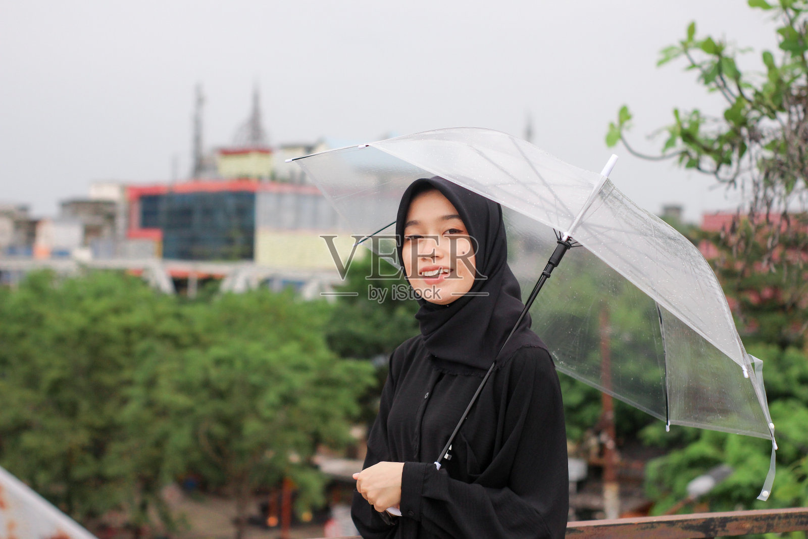 快乐的亚洲女人撑着伞站在城市公园里照片摄影图片