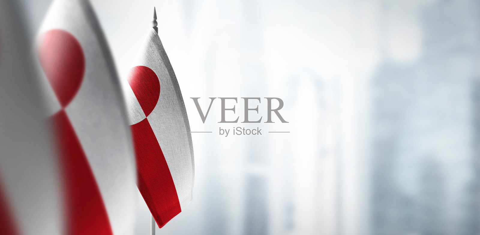 城市模糊的背景上挂着格陵兰岛的小旗照片摄影图片