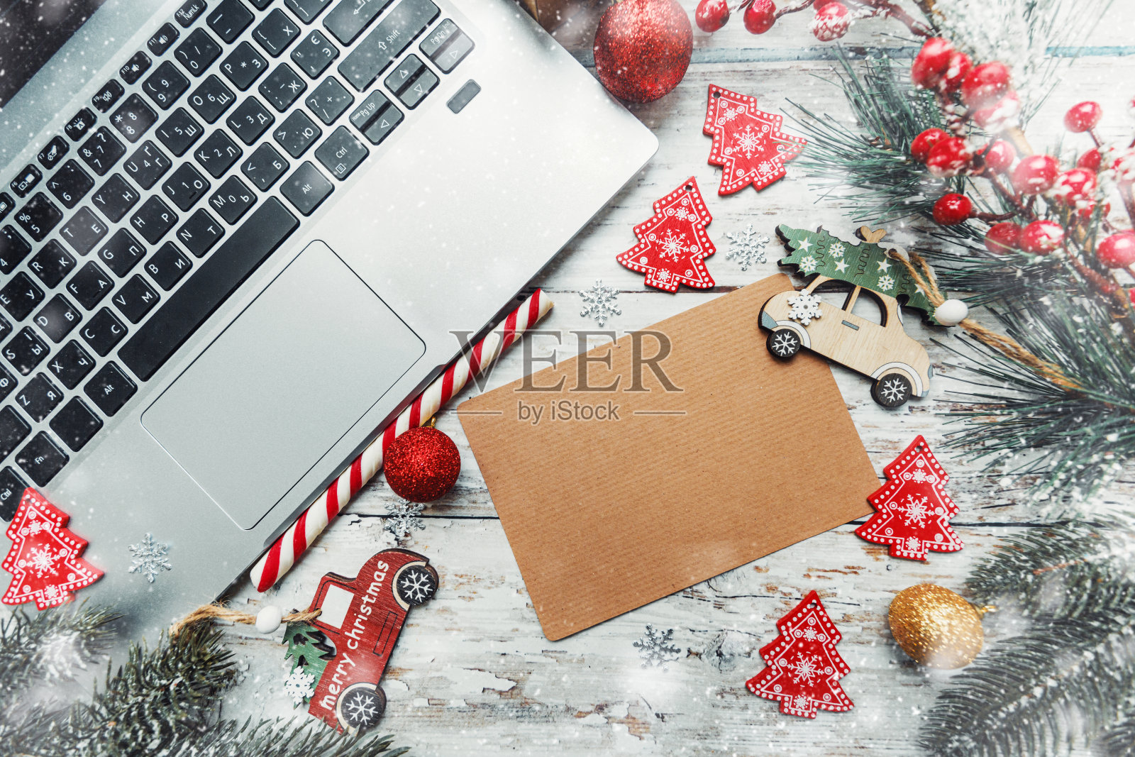 圣诞背景与新年玩具,笔记本电脑和写文字的卡片在木制背景与雪花。照片摄影图片