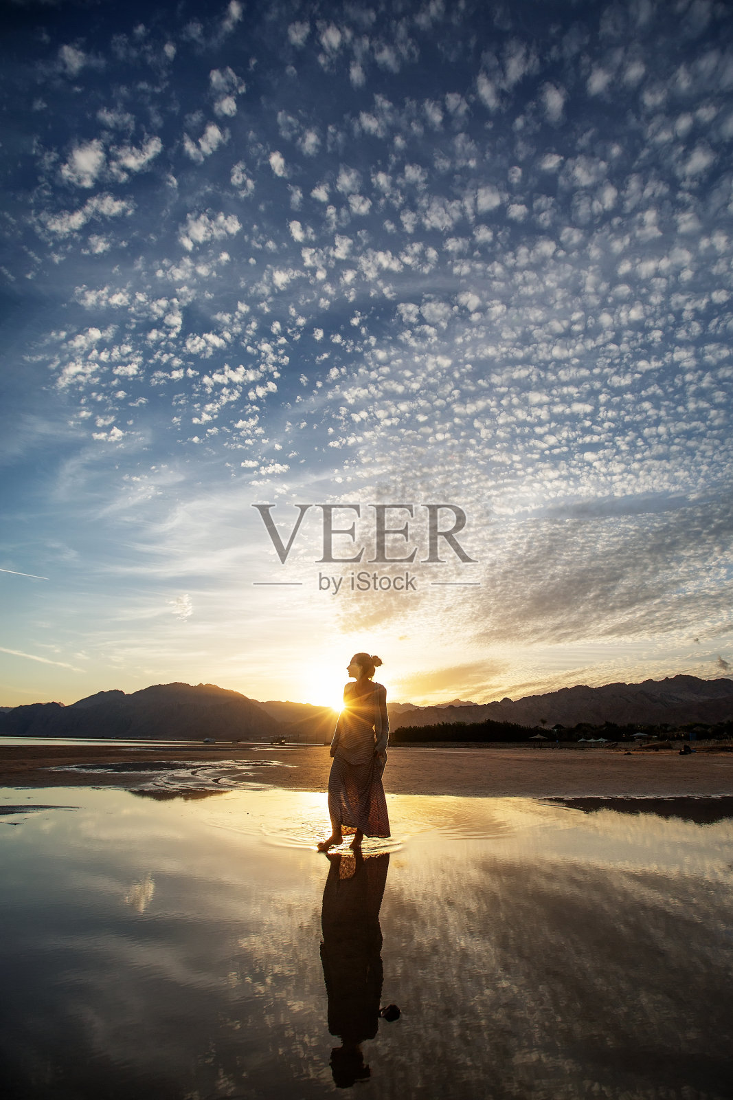 美丽的女人在日落时在海边跳舞照片摄影图片