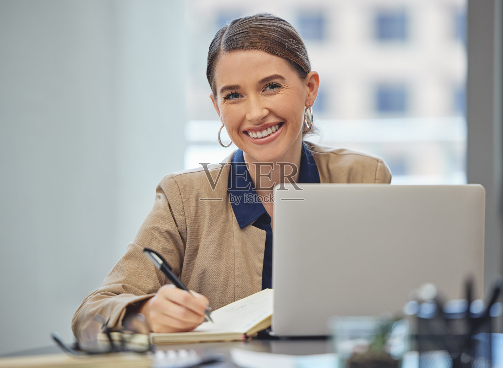 一个迷人的年轻女商人独自坐在办公室里写笔记照片摄影图片