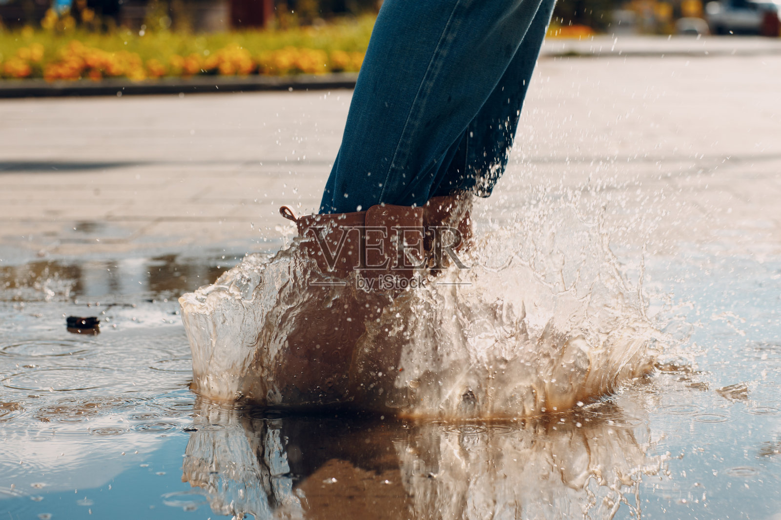 穿着雨靴的女子在秋雨中走着、跑着、跳进水坑里,水花四溅,水花四溅照片摄影图片