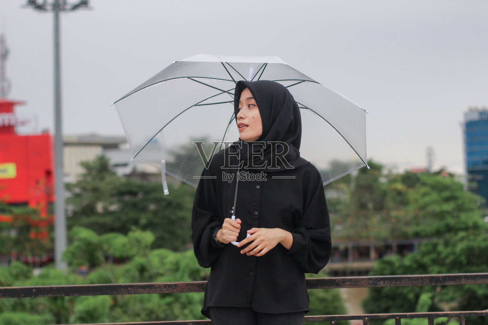 亚洲妇女打着伞站在城市公园里照片摄影图片