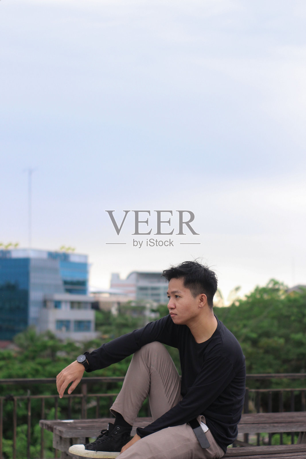 亚洲男人坐在城市公园里享受照片摄影图片