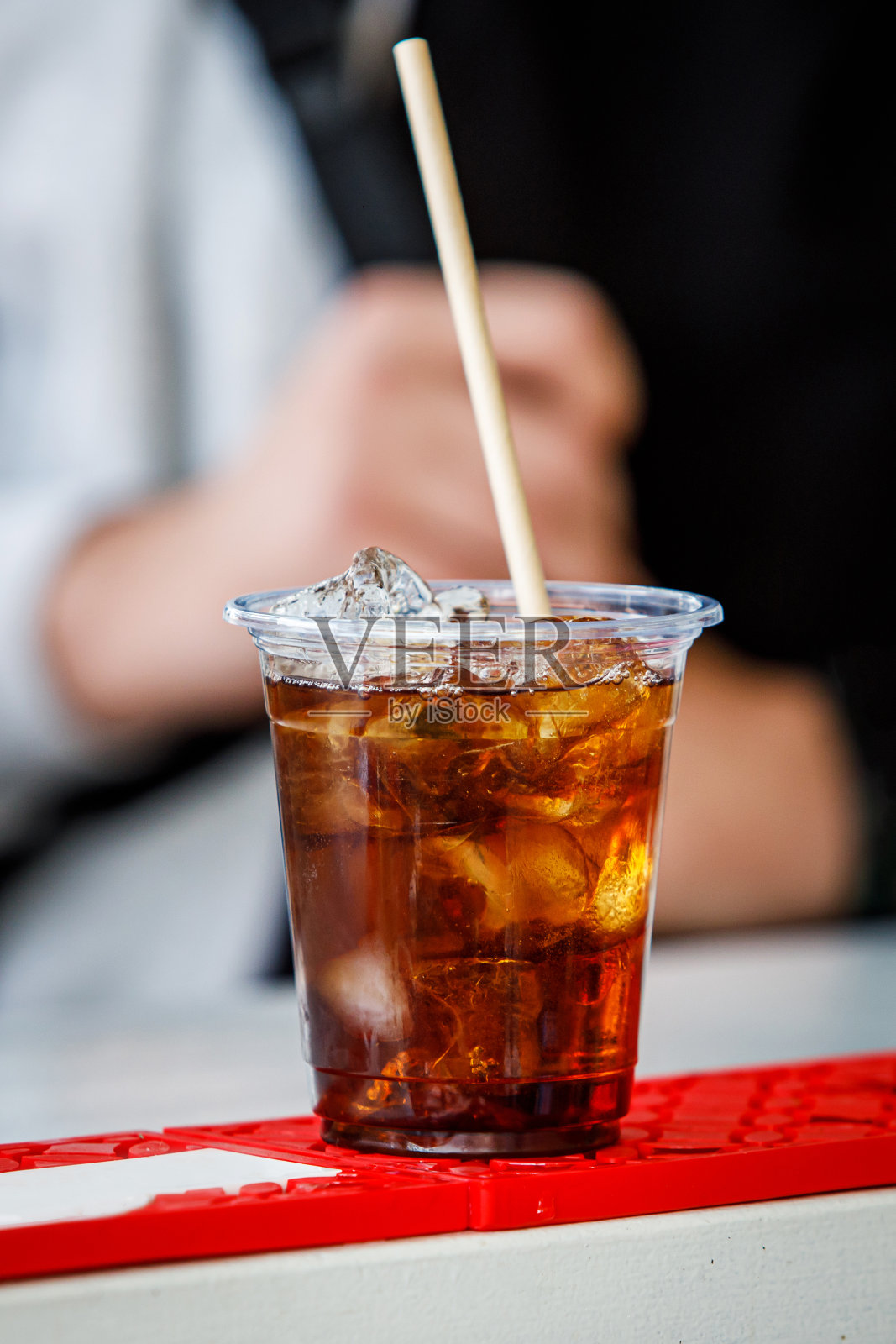 塑料杯加可乐和冰的鸡尾酒。照片摄影图片