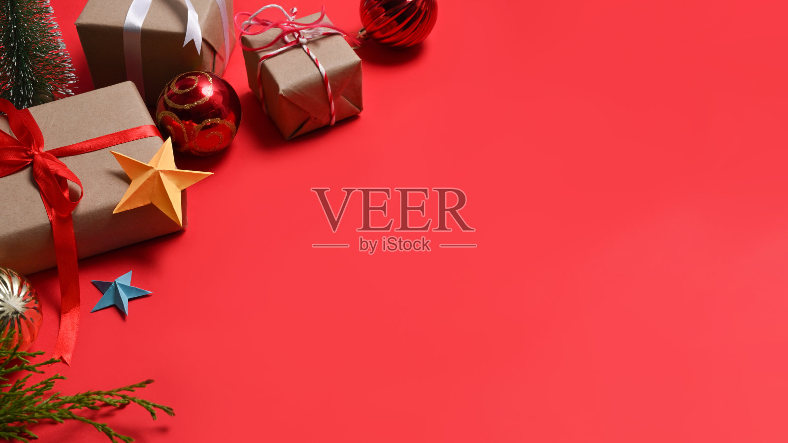 礼品盒和冷杉树枝上的红色背景。圣诞节和新年的概念。照片摄影图片