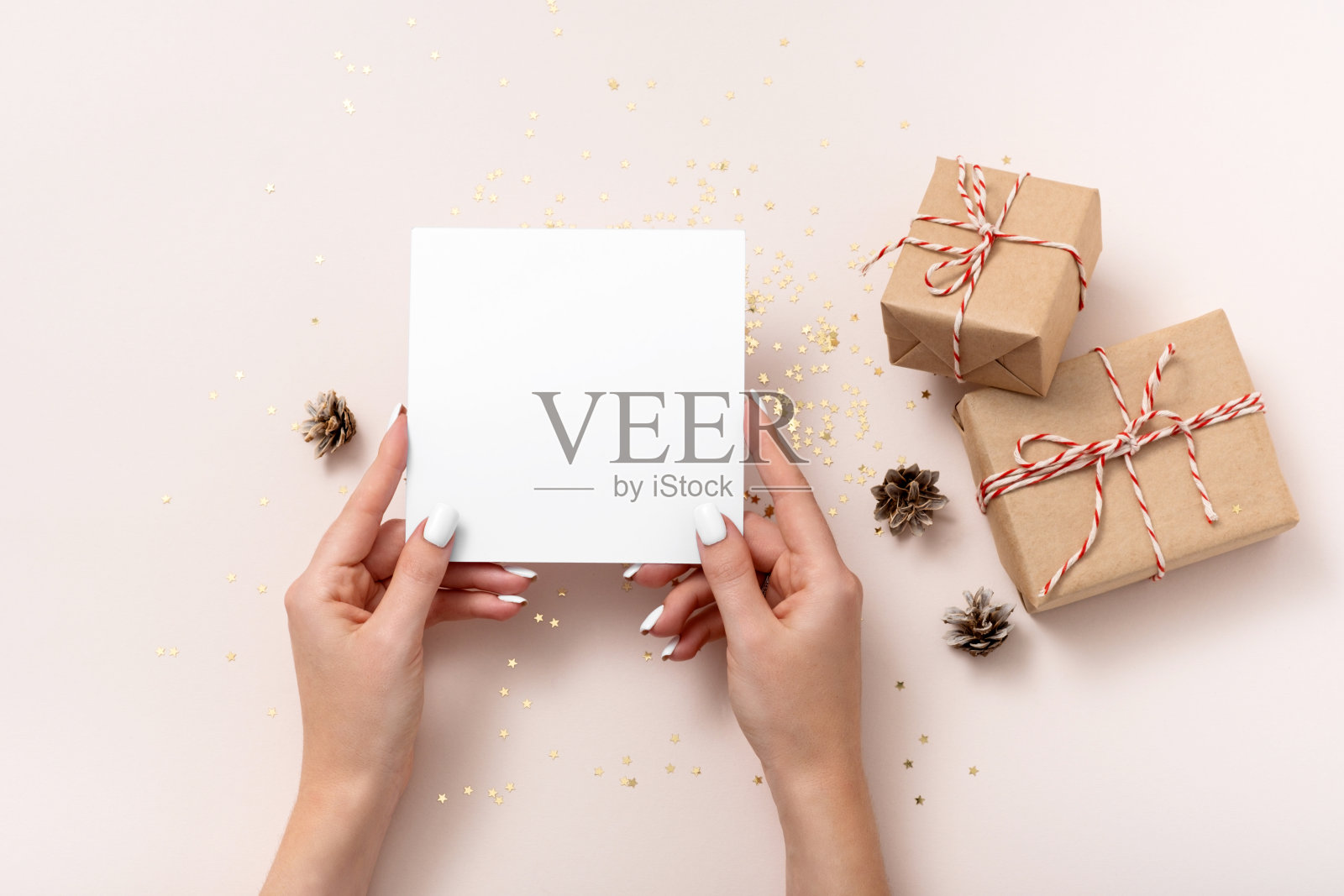 圣诞节。空白的正方形纸模型,金色的星星五彩纸屑,碰撞,米色背景上的礼盒照片摄影图片