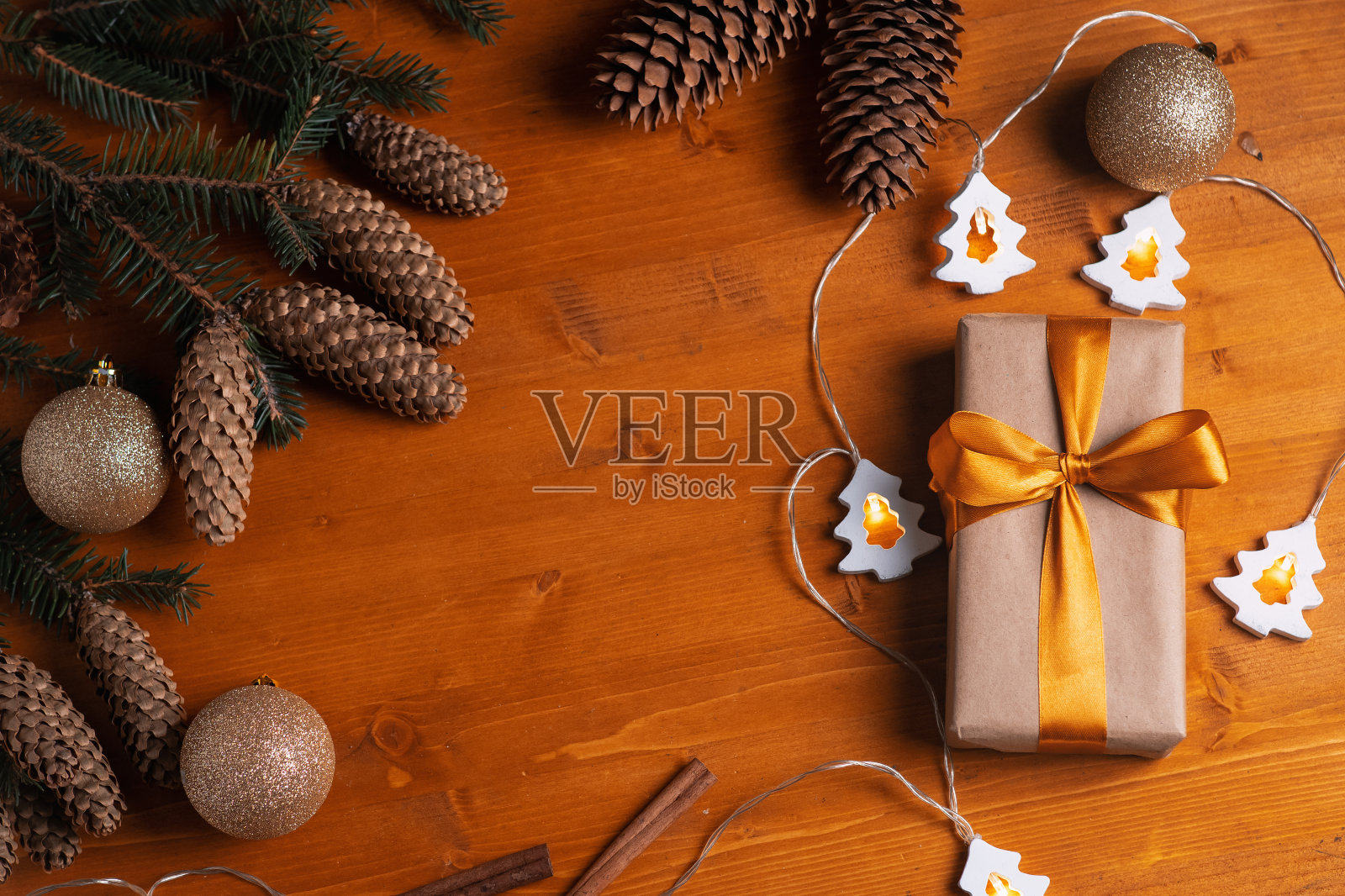 节日贺卡,顶视礼品盒与金丝带,圣诞树的树枝和锥,天然木桌。圣诞节组成照片摄影图片