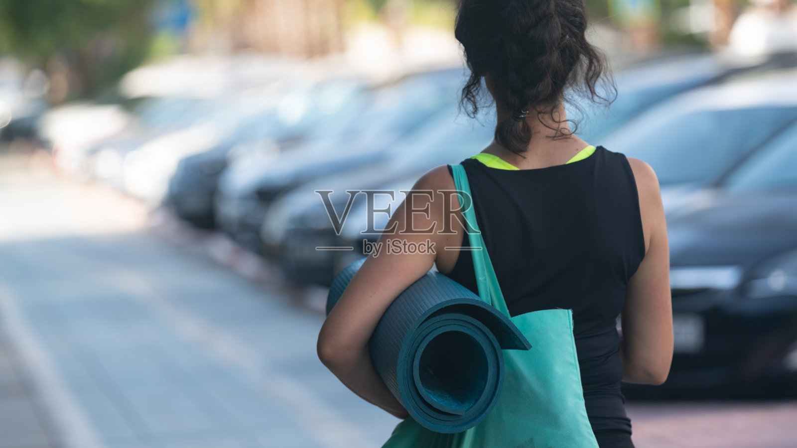 中年妇女拿着瑜伽垫走在人行道上照片摄影图片