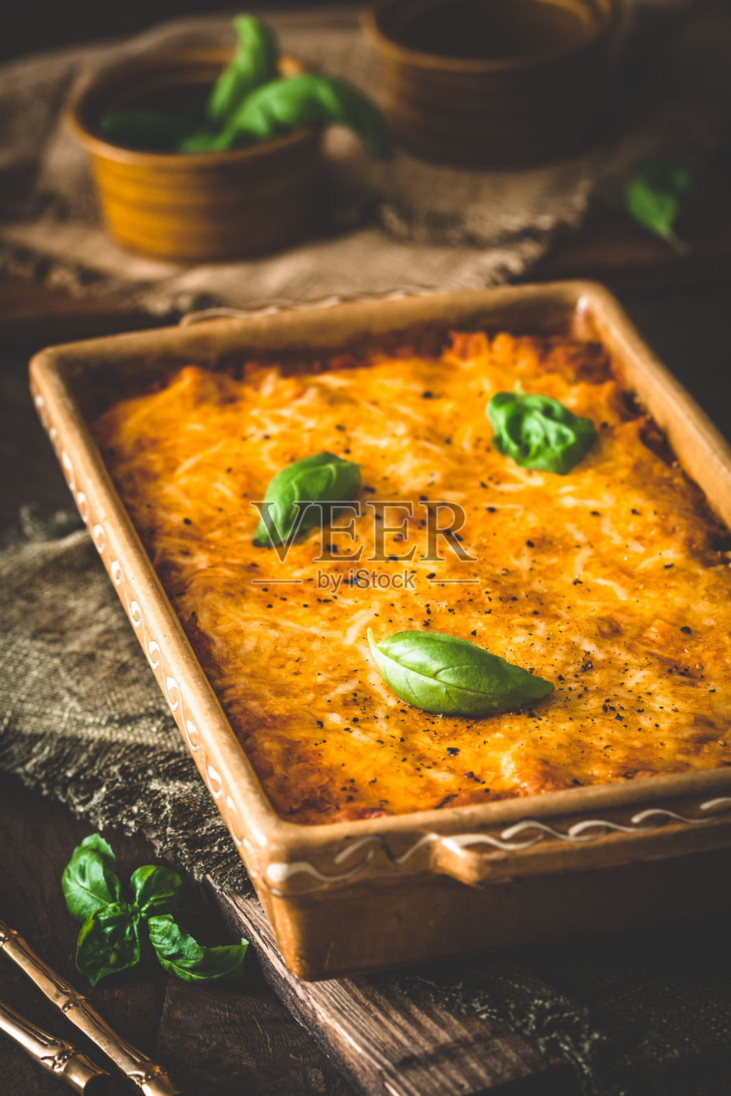 烤意大利面和奶酪,配上番茄酱和罗勒,木制背景,垂直照片摄影图片
