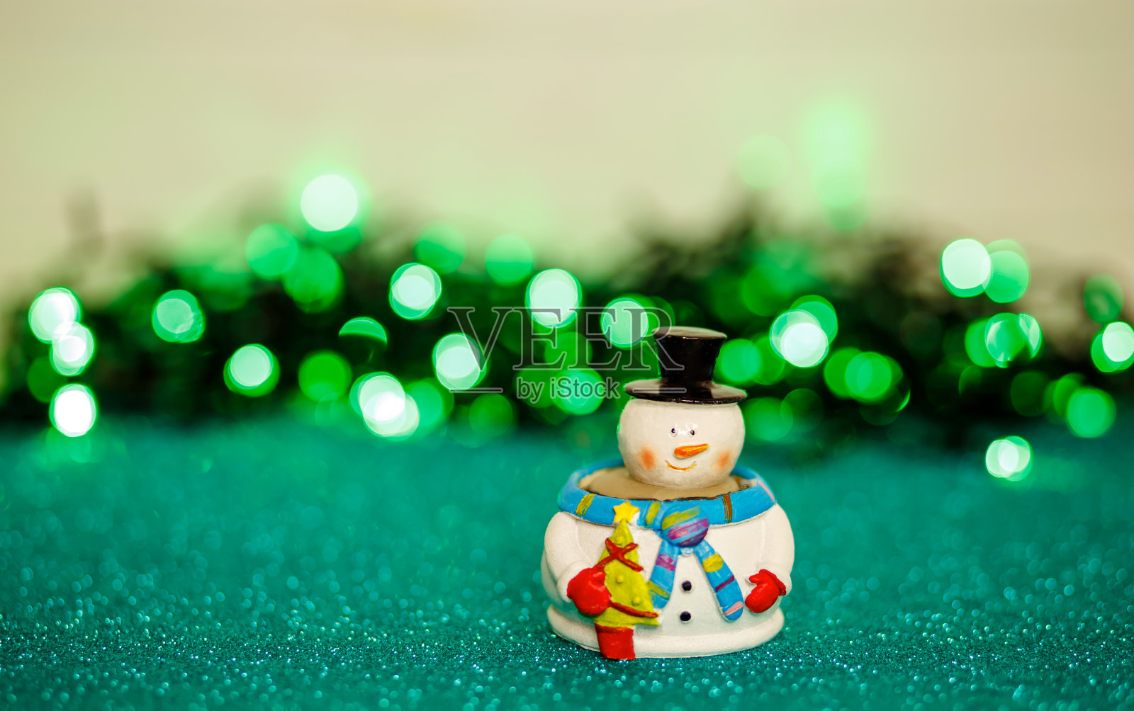 散焦圣诞灯前的小雪人玩具。节日卡片照片摄影图片