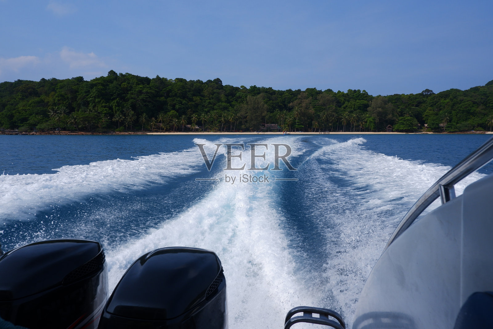 快艇从岸边驶来,白色的波浪点缀着深蓝色的大海。照片摄影图片