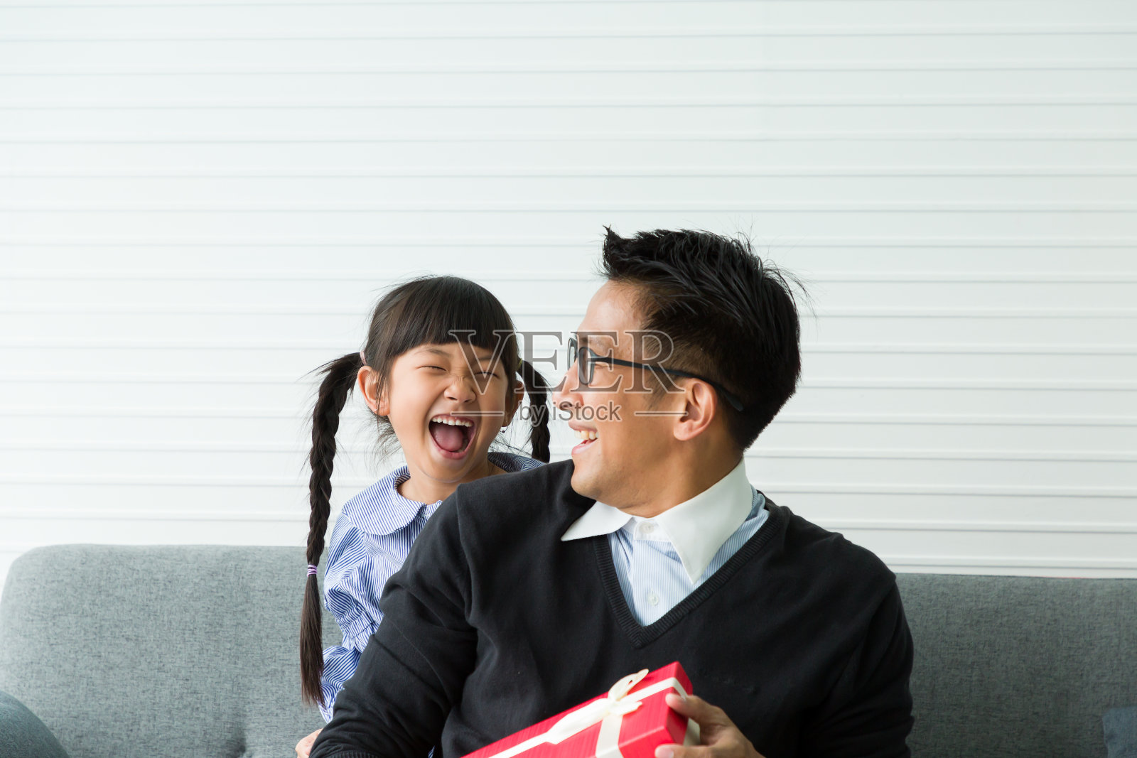 年轻的亚洲爸爸和可爱的小女儿在家里的沙发上玩礼品盒照片摄影图片