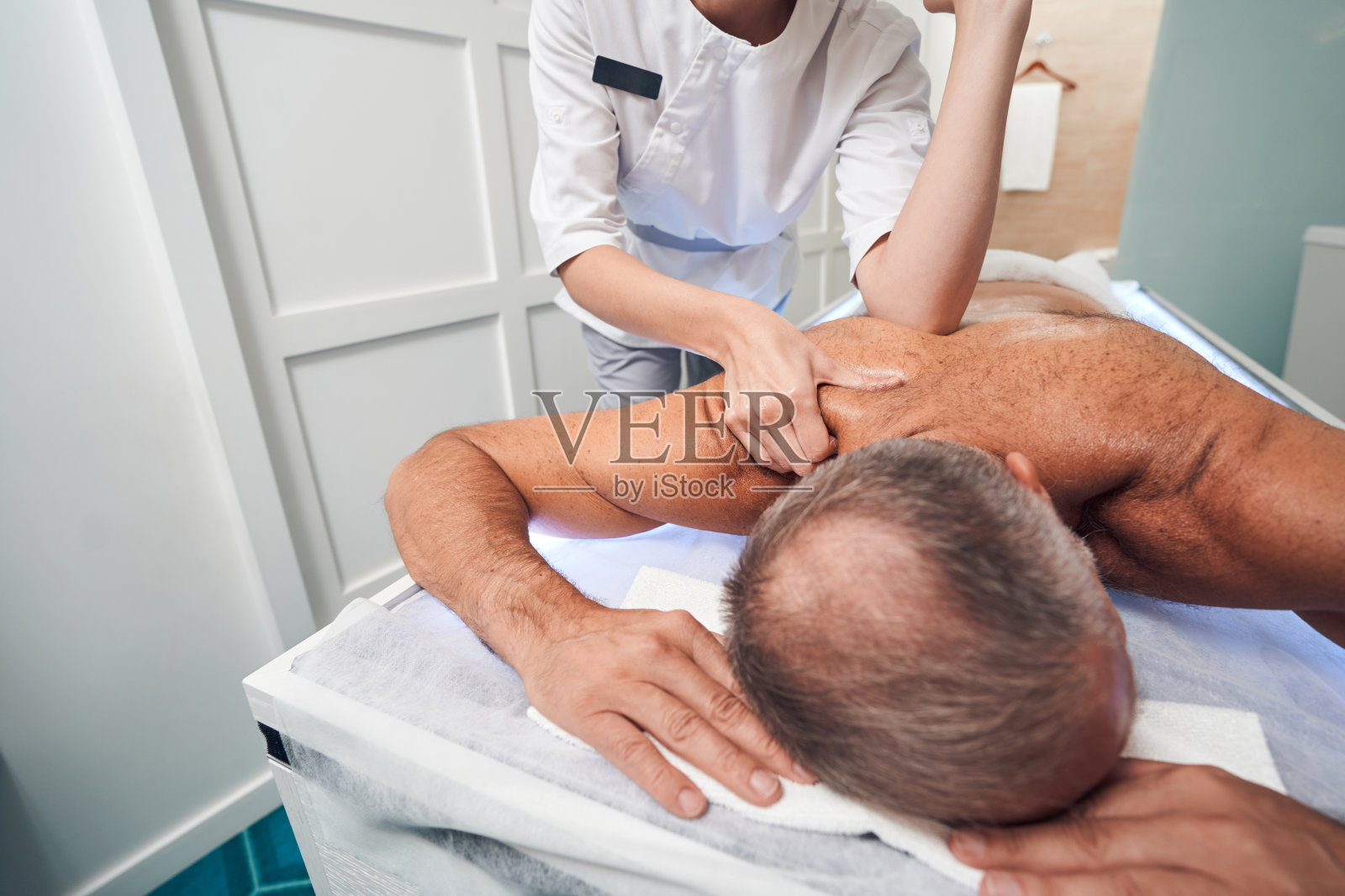 在水疗沙龙接受背部按摩的男性照片摄影图片