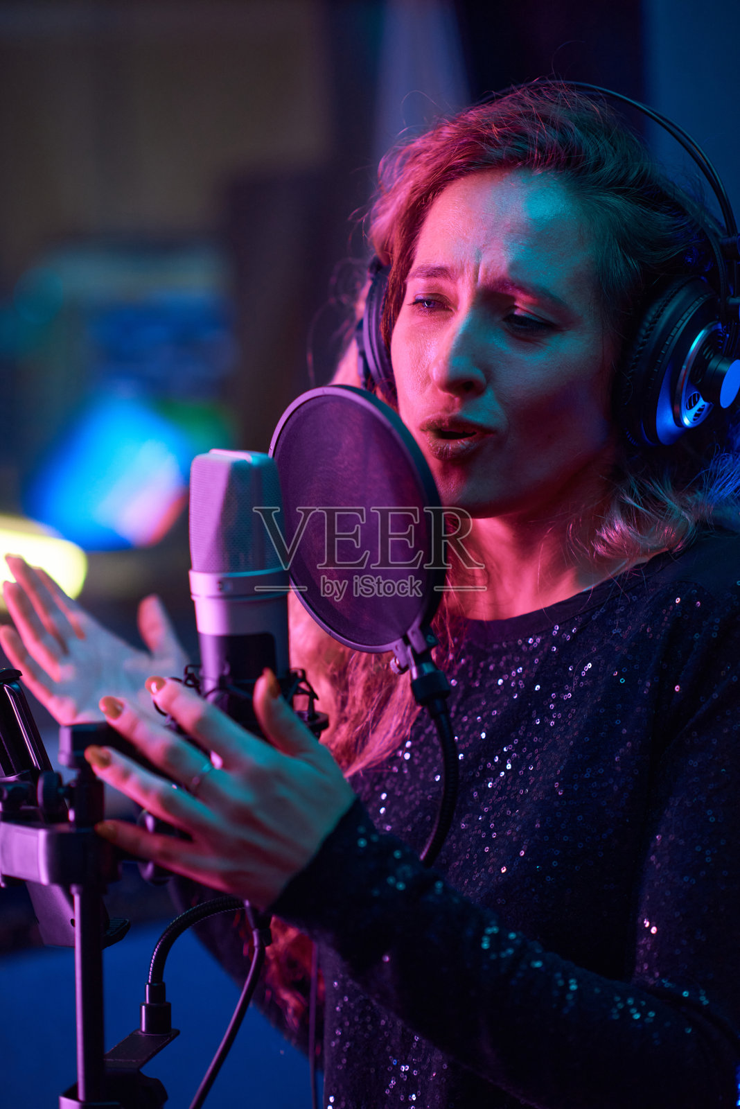 歌手在演播室对着麦克风唱歌照片摄影图片