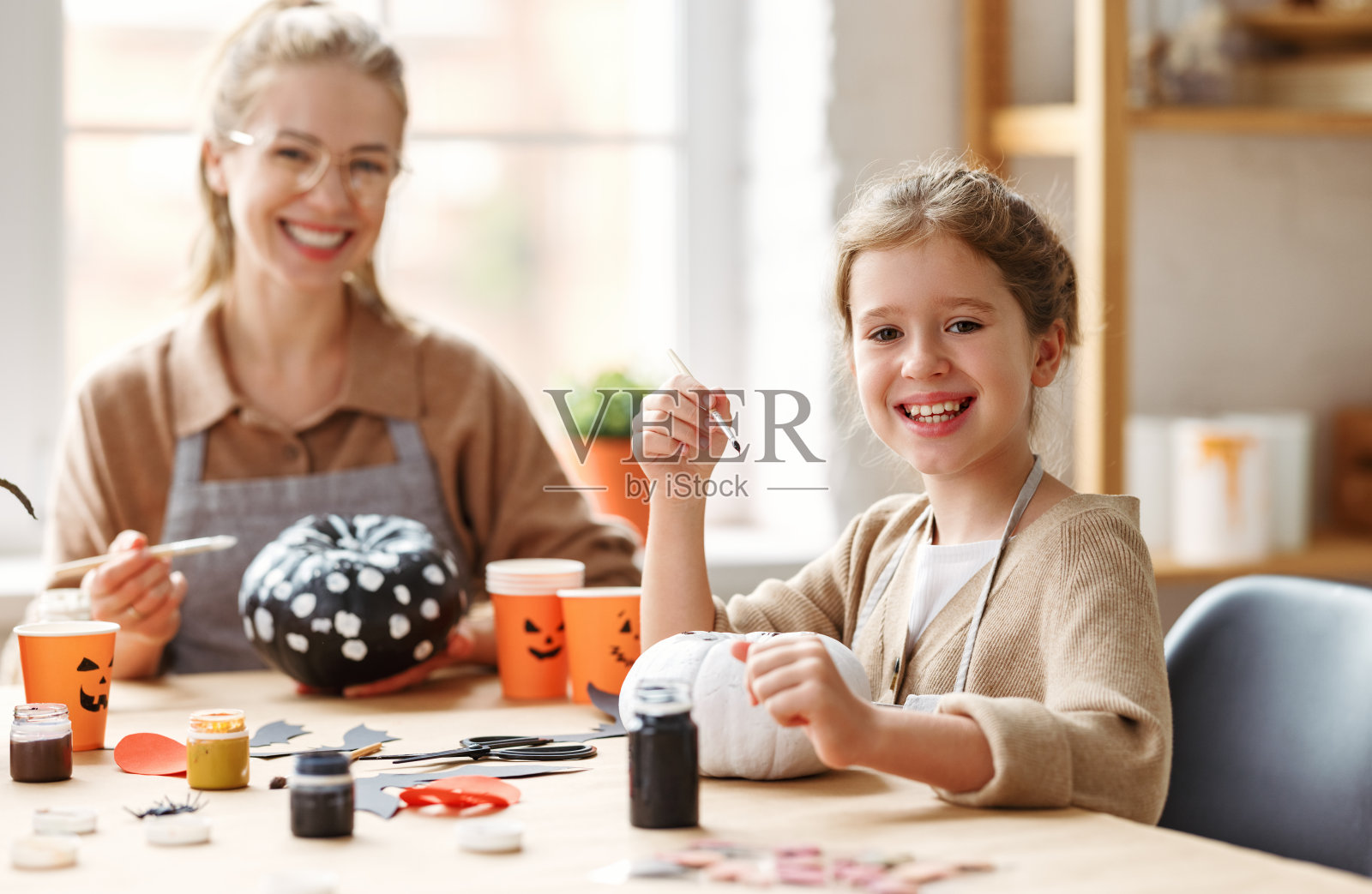 可爱的小女孩和妈妈在家里画万圣节南瓜照片摄影图片
