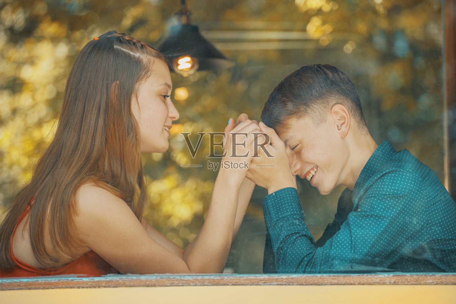 一对年轻漂亮的夫妇在玻璃后面的咖啡馆里照片摄影图片