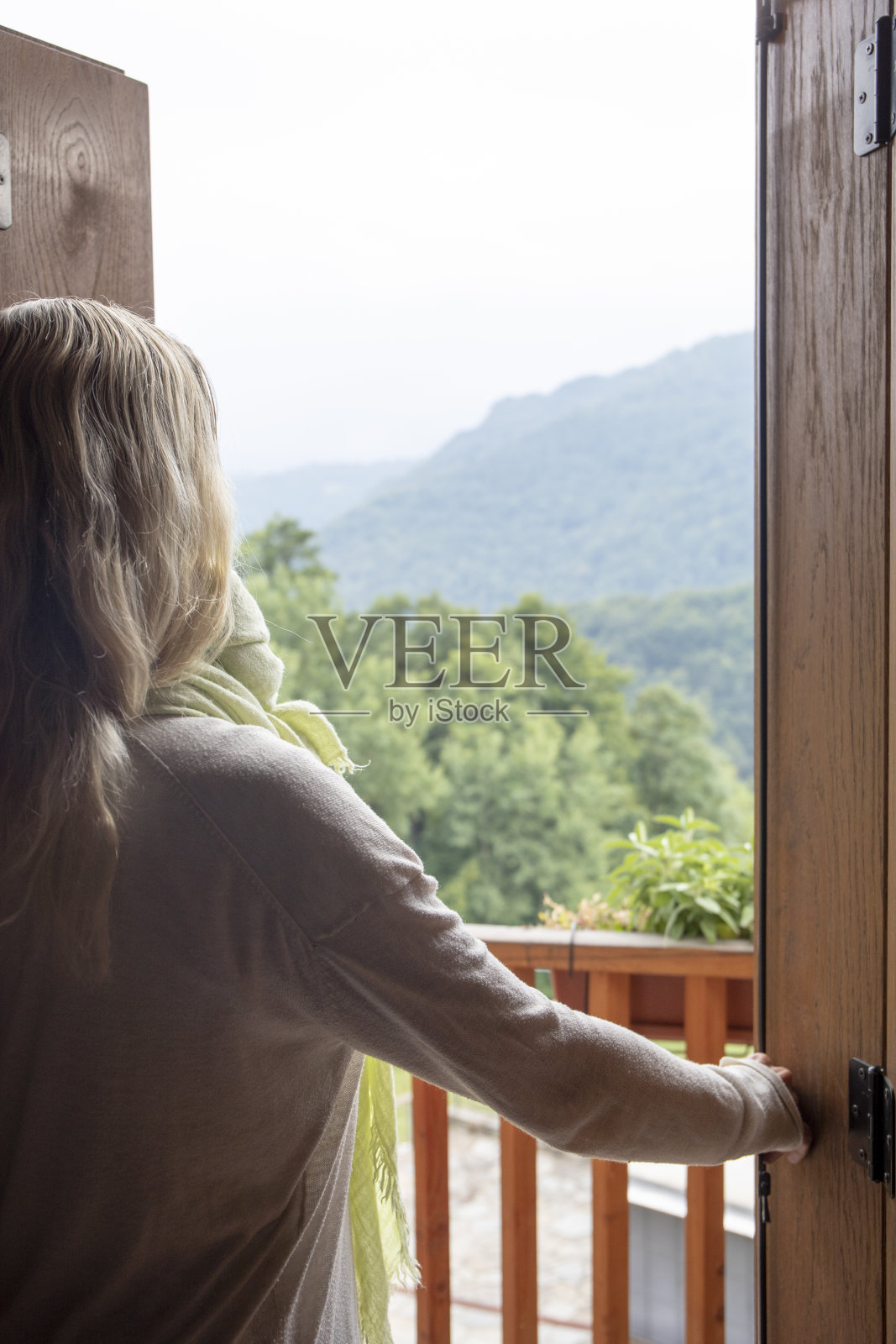 女人穿过门口来到阳光明媚的阳台上照片摄影图片