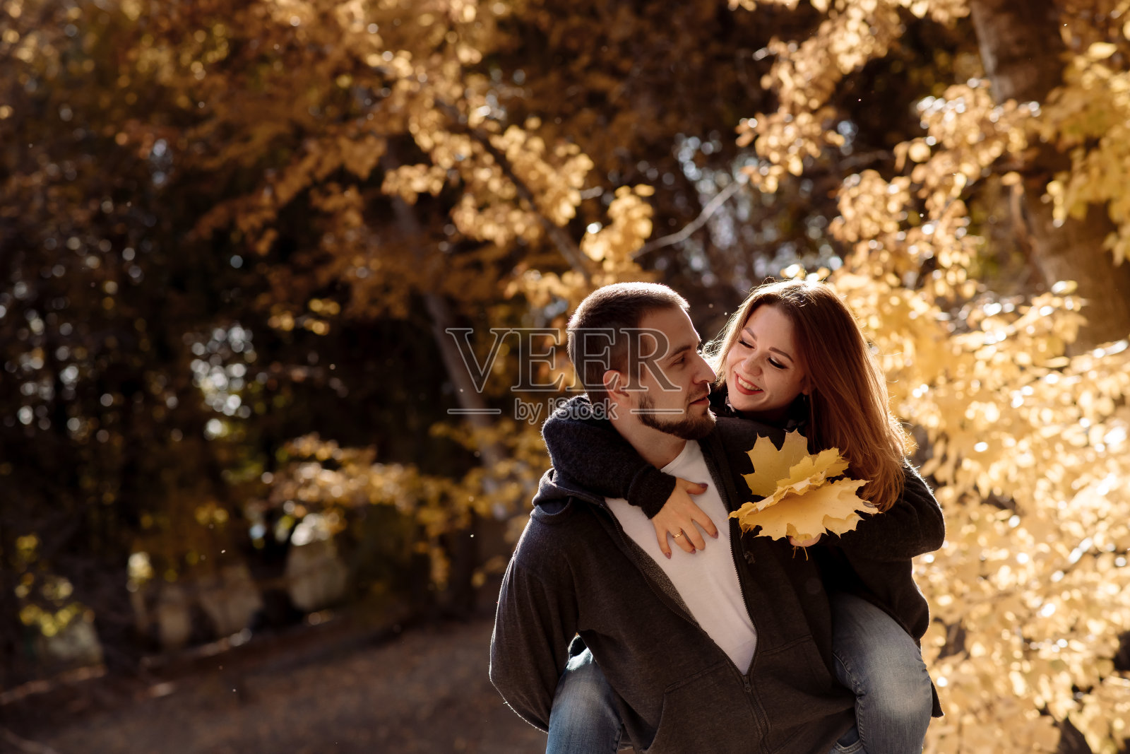 秋叶落的公园里,一对美丽的年轻男女在池塘边拥抱照片摄影图片