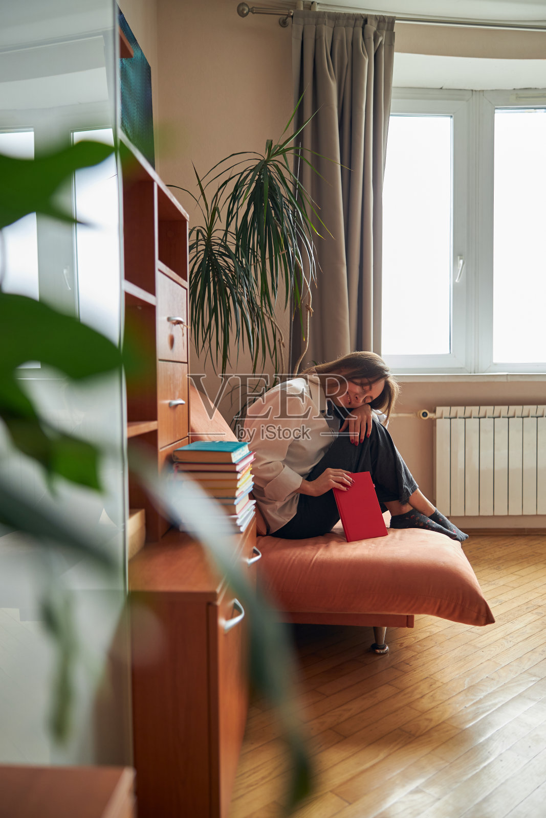 年轻,开朗,自信,快乐的女人在她舒适的扶手椅放松与书在家里照片摄影图片