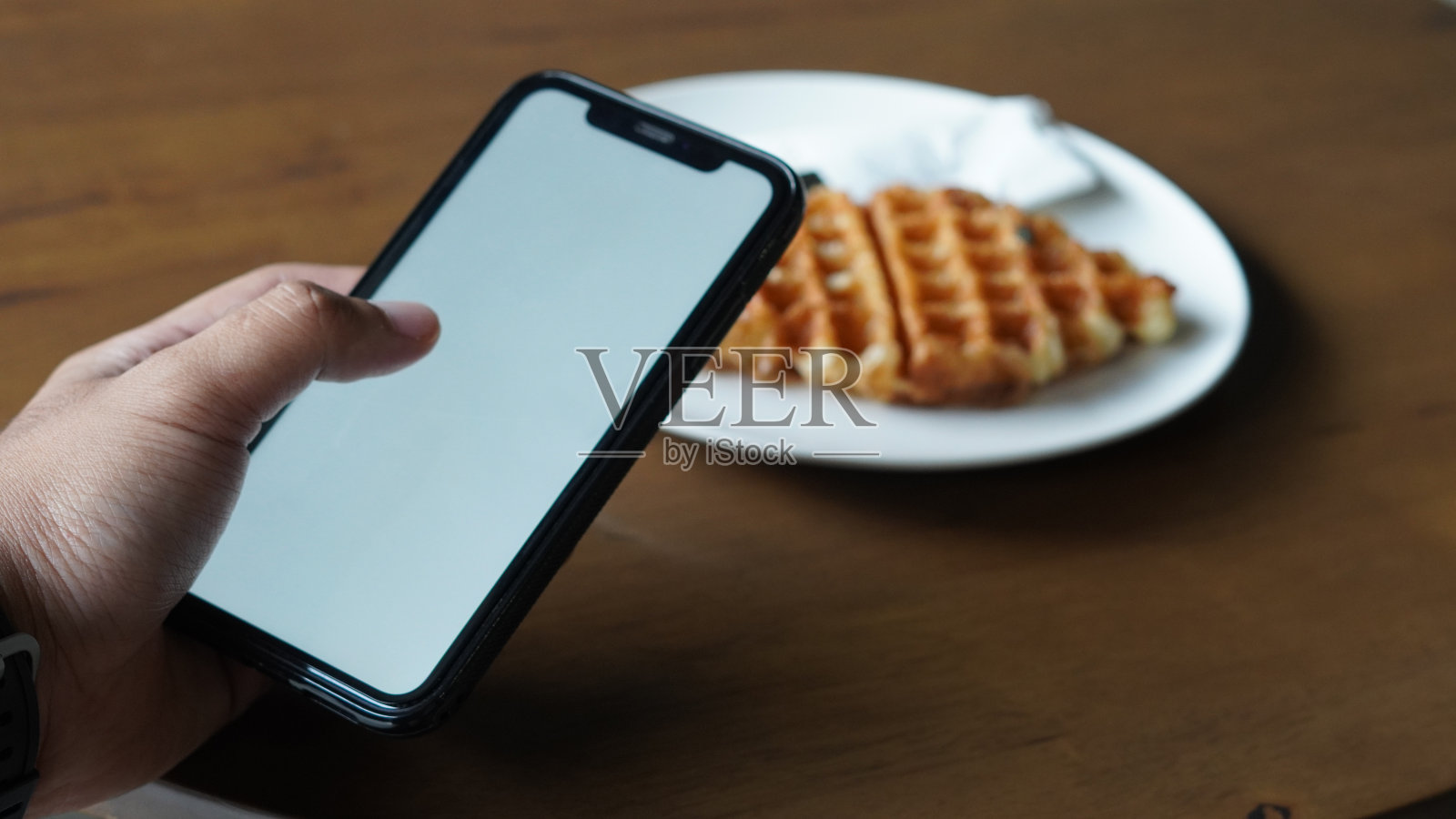 拿着智能手机,面前放着食物的模型照片摄影图片