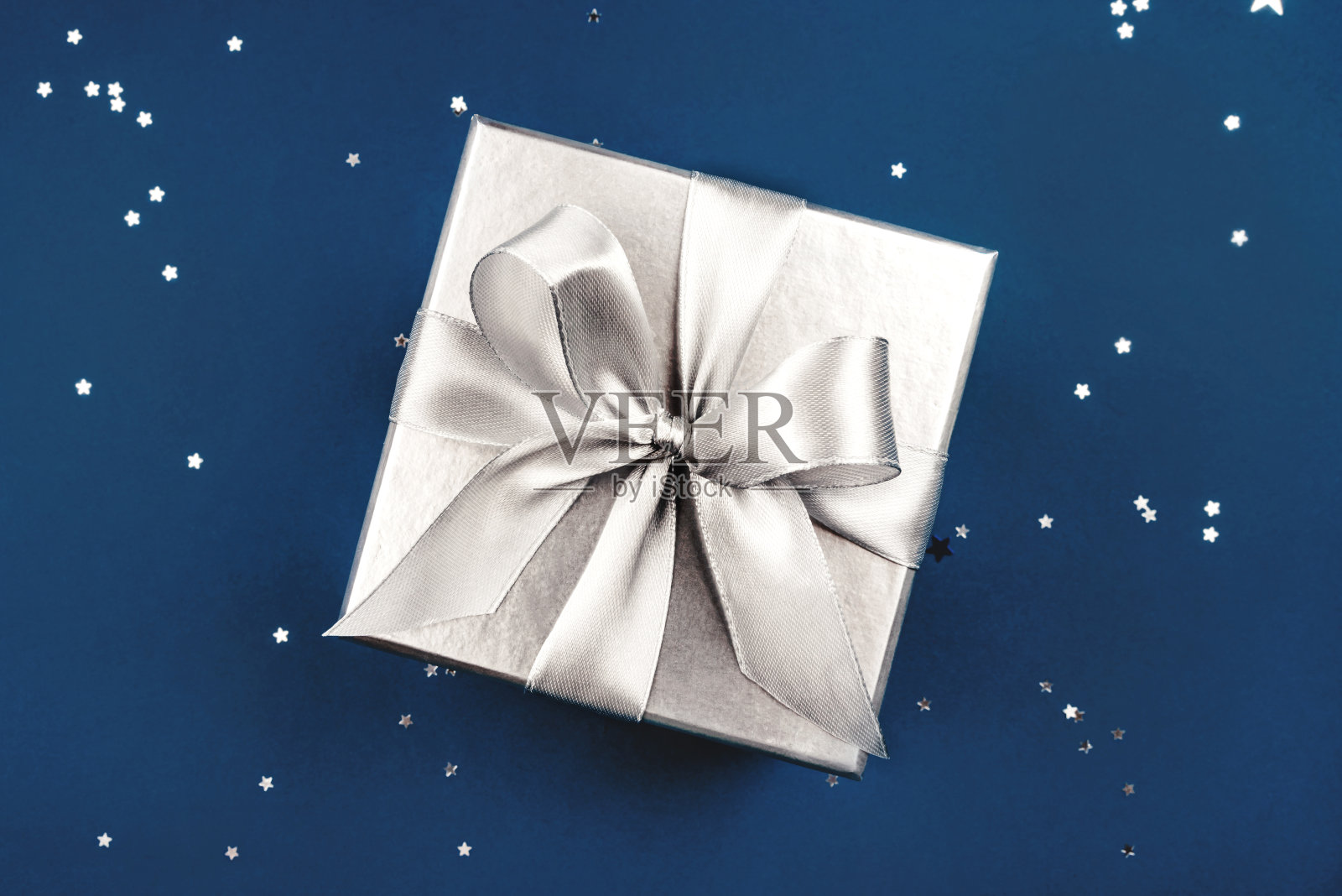 蓝色背景上有蝴蝶结的银礼盒。照片摄影图片