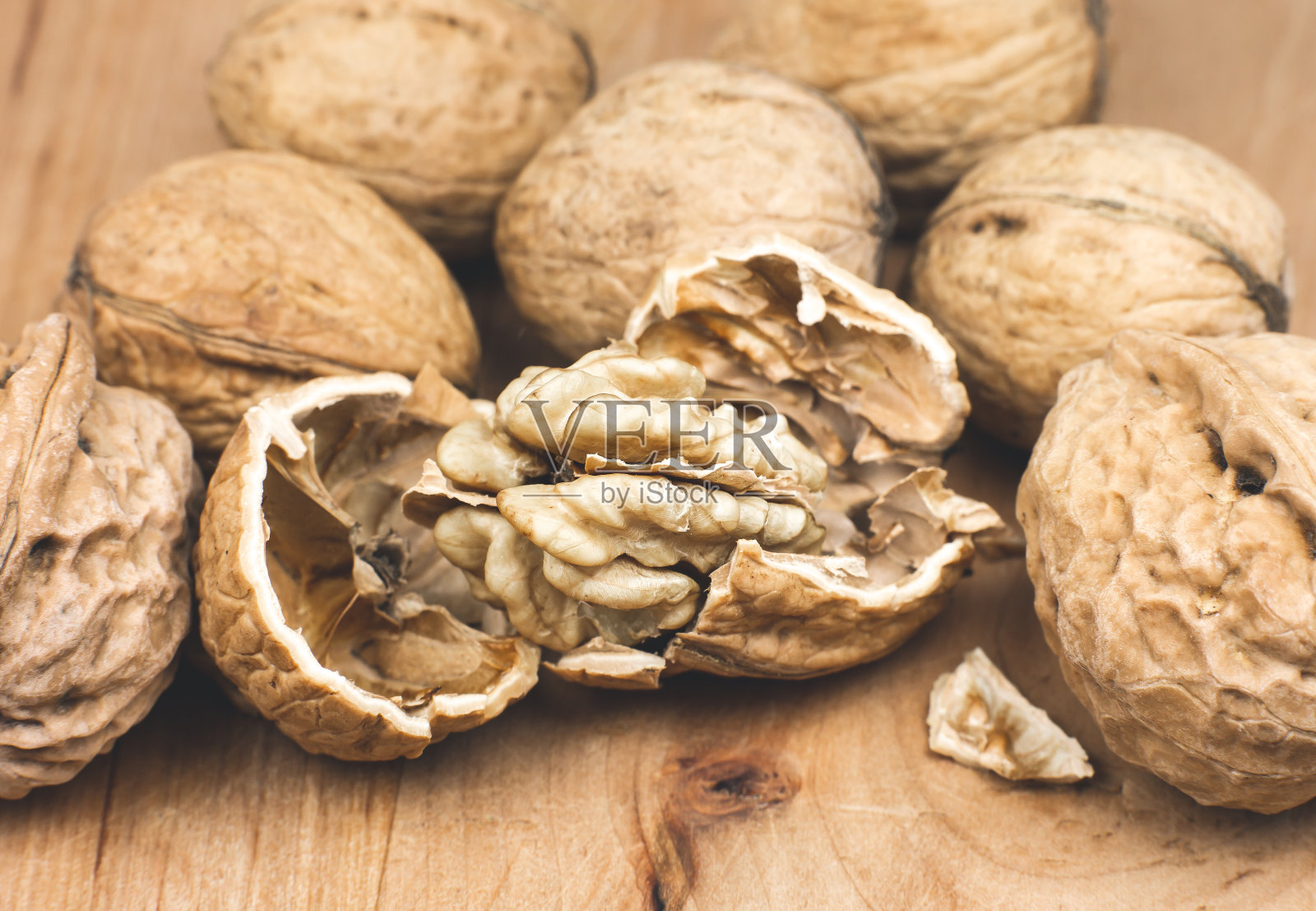 木质背景上的碎核桃。关闭了。照片摄影图片