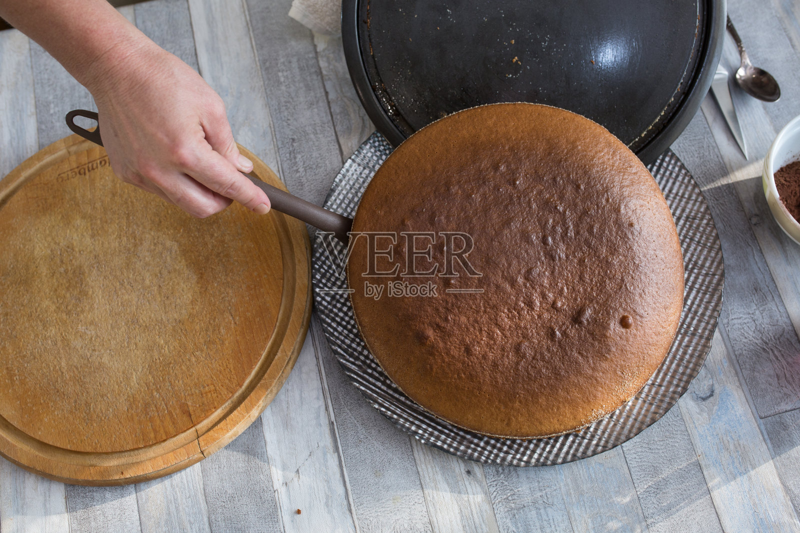 制作酸奶油巧克力蛋糕的步骤。女人们的手把烤好的蛋糕从烤箱里拿出来,放在盘子上。照片摄影图片