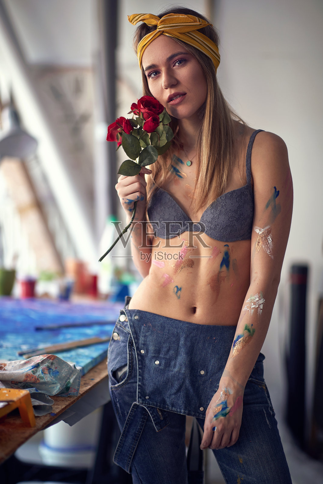 一名性感迷人的女艺术家在她的工作室里与玫瑰摆造型,休息时绘画。艺术、绘画、工作室照片摄影图片