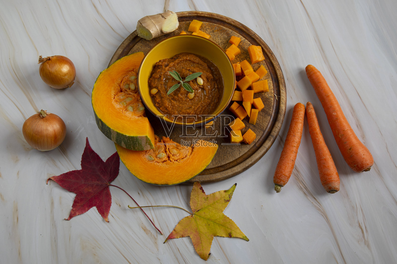 秋菜,南瓜汤煮。南瓜放在木板上,旁边是洋葱、胡萝卜和姜照片摄影图片