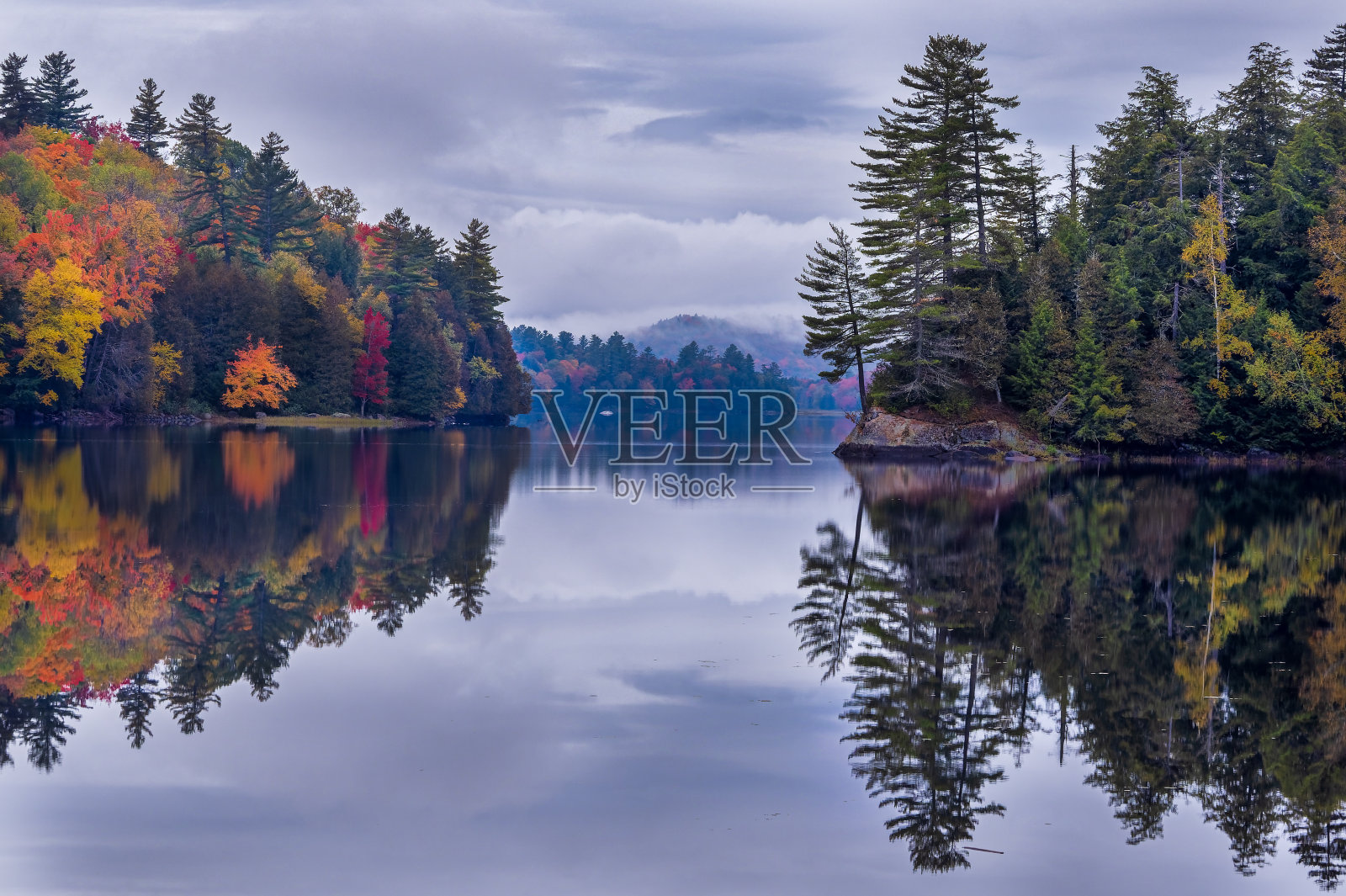 秋天的彩色树木倒映在池塘与戏剧性的天空照片摄影图片