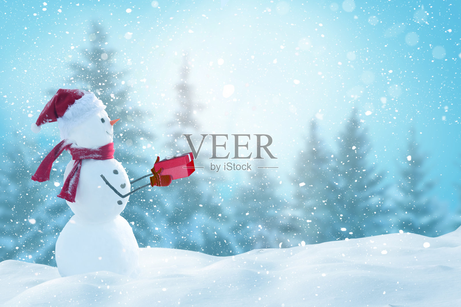 可爱微笑的雪人拿着红色的礼品盒。冬天的童话。圣诞快乐,新年快乐贺卡与复制空间照片摄影图片