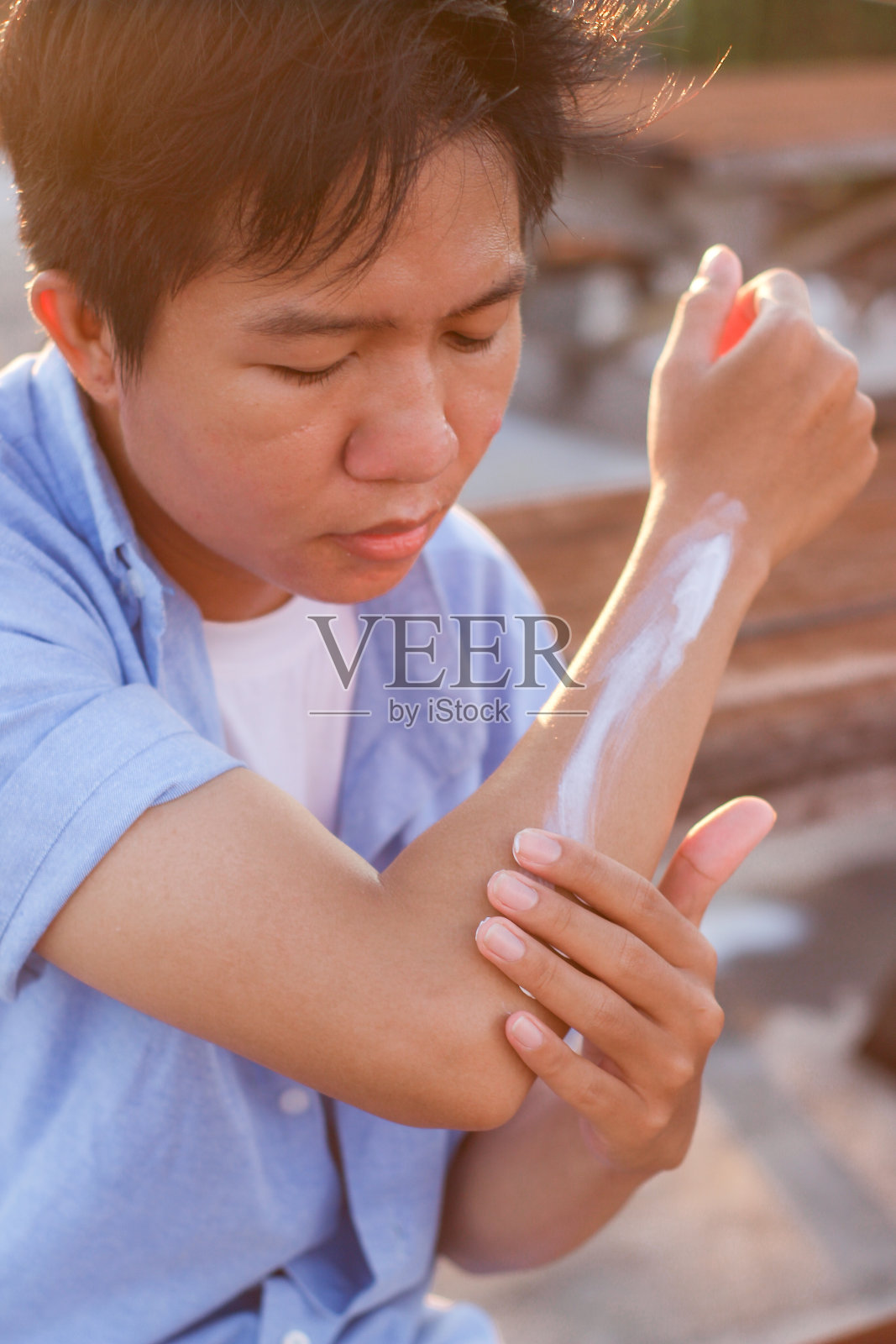 年轻人坐在户外使用防晒霜照片摄影图片