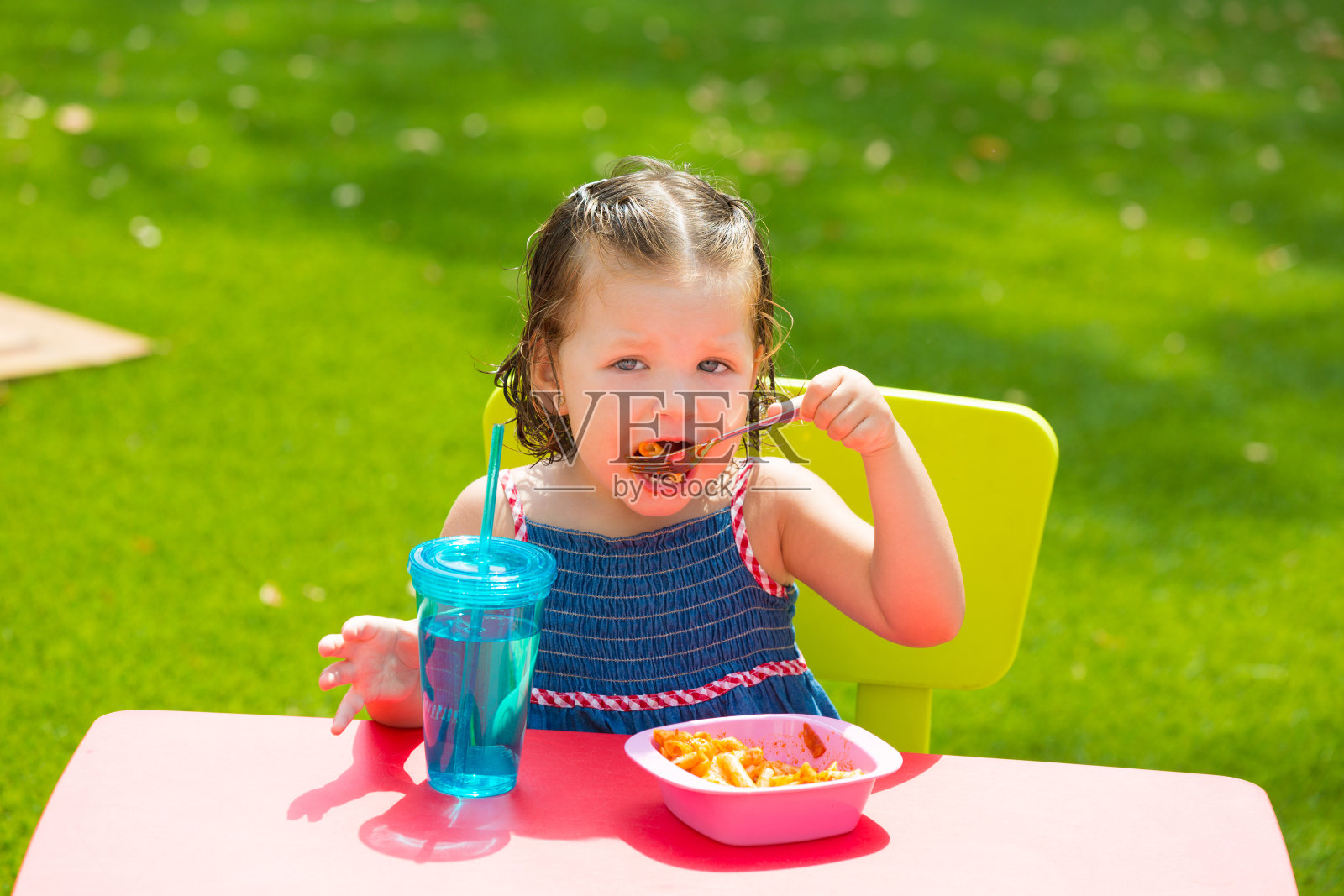蹒跚学步的小女孩在吃通心粉番茄通心粉照片摄影图片