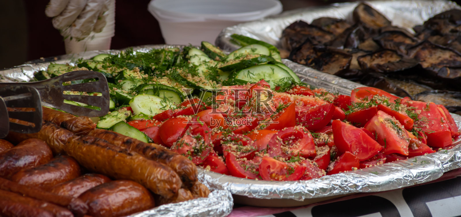美食广场的柜台上放着烤香肠、蔬菜和沙拉。街头食品照片摄影图片